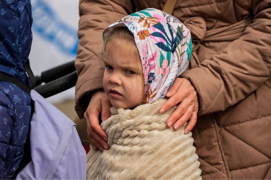 A refugee child waits in a line after fleeing the war from neighboring Ukraine at the border crossing in Medyka, southeastern Poland, Sunday, April 10, 2022. Image: AP Photo/Sergei Grits