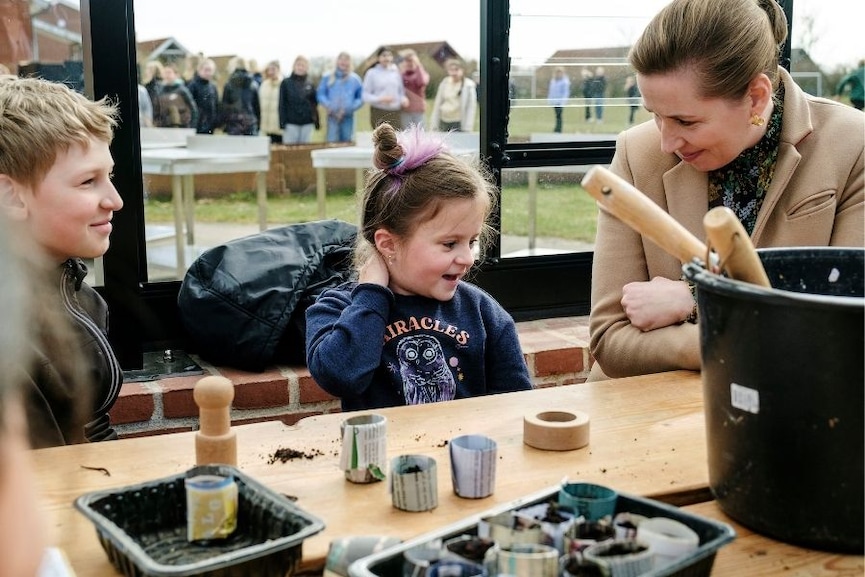 Danish Prime Minister Mette Frederiksen, right, meets Ukrainian refugee children at Paradisbakken school in Nexoe, as she visits the island of Bornholm in Denmark, Thursday, April 7, 2022. Anna Prokopiuk, center, is from Ukraine but has lived in Denmark for three years and is therefore able to help interpret for the newly arrived refugees. Image: Pelle Rink/Ritzau Scanpix via AP