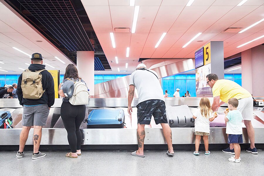 Flyers reclaim their baggage at John F. Kennedy International airport in New York, July 29, 2022. Many higher income households have been able to keep spending even as costs climb, but data and anecdotes suggest that lower-income households, despite the resilient job market, are struggling more profoundly with inflation. (Gus Powell/The New York Times)