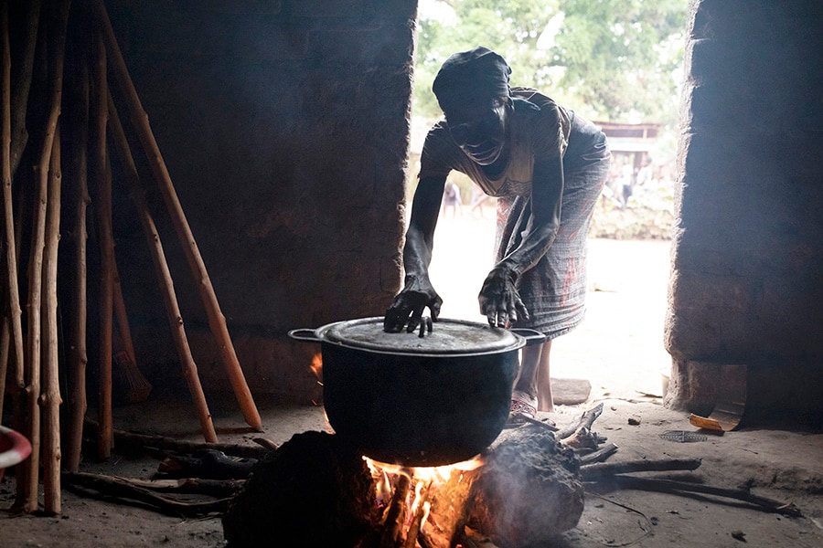 Eyenga Ekwabe, 60, cooks cassava bread in a small town south of Mbandaka, Democratic Republic of Congo, on March 17, 2022. In the Congo River Basin, a rainforest that rivals the Amazon in importance, people who collect bundles of wood to make charcoal play a surprisingly large role in deforestation. (Ashley Gilbertson/The New York Times)