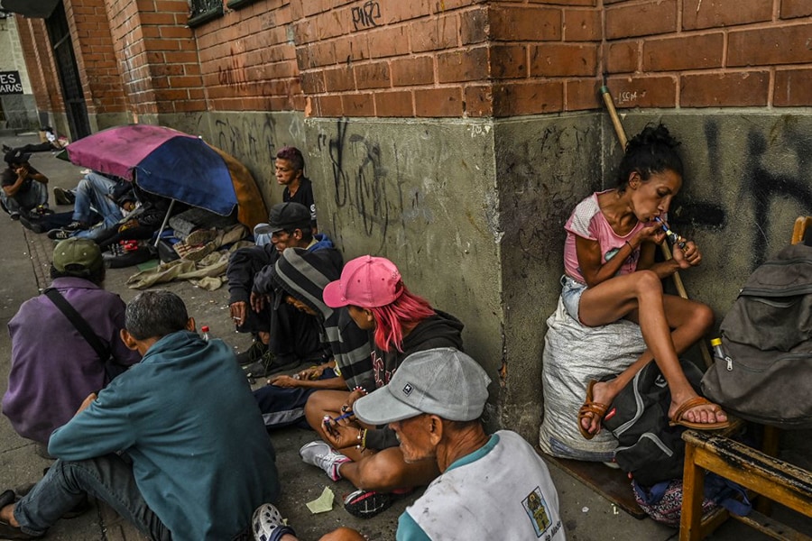Drug addicts smoke basuco, a highly addictive drug consisting of low-grade cocaine mixed with coca paste and other substances, in downtown Medellin, Colombia, on February 28, 2022. Three decades after Pablo Escobar's shot body was left on a Medellin rooftop, drug trafficking continues and, at present, markets for flavored cocaine, local crack, pharmaceutical drugs and ketamine-based hallucinogens are rife for in his hometown. (Credits: JOAQUIN SARMIENTO / AFP)
