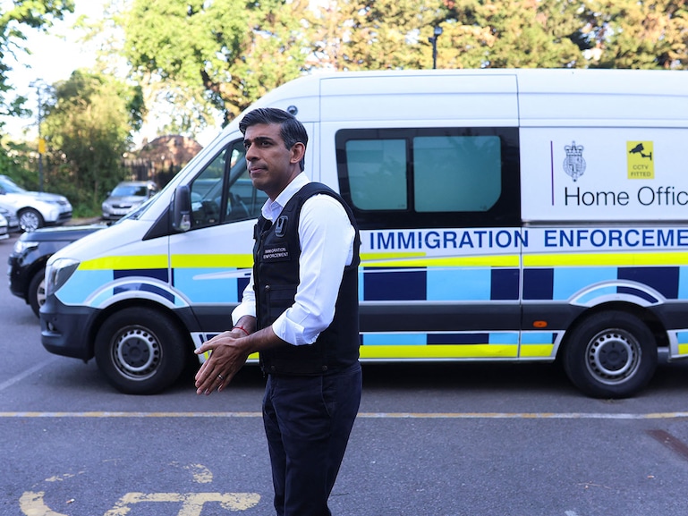 British Prime Minister Rishi Sunak stands alongside an immigration van at Wembley Police Station in northwest London, Britain, June 15, 2023. Sunak, dressed in a bullet-proof vest, joined the enforcement officials on a raid as part of a nationwide crackdown on illegal migration, which ended in the arrest of over a hundred foreign nationals.