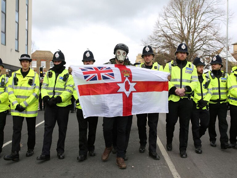 A flag-waving nationalist, anti-immigration protester is surrounded by police officers during a march in Dover, England, on March 4, 2023.