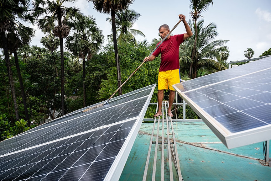 Jibu Thettayil cleans solar panels, which have helped bring down his electricity bill to zero.