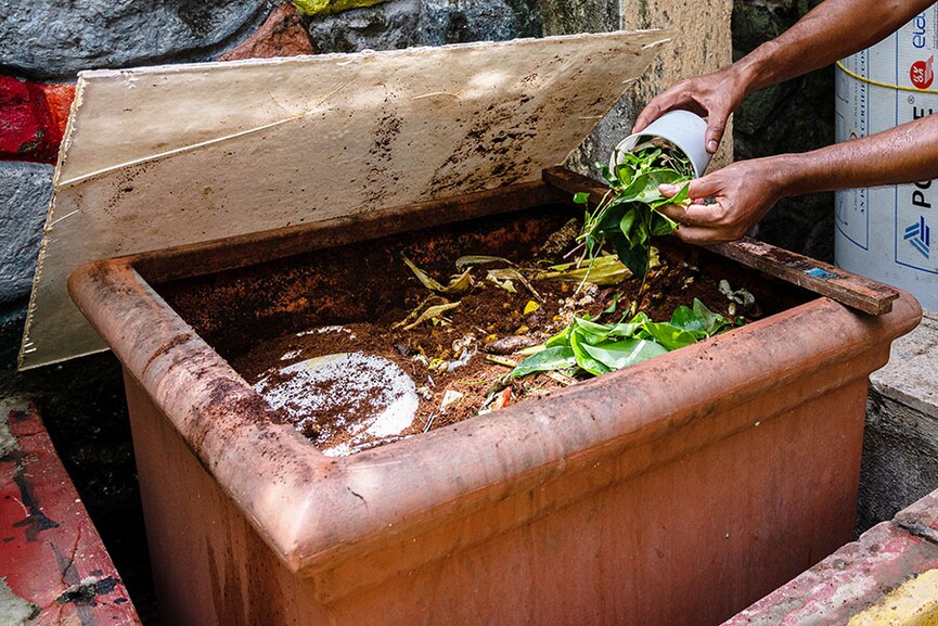 Chetan Soorenji, a Tata employee by profession, puts green leaves in a chamber where he produces compost, located in the backyard of his house at Chembur in Mumbai.