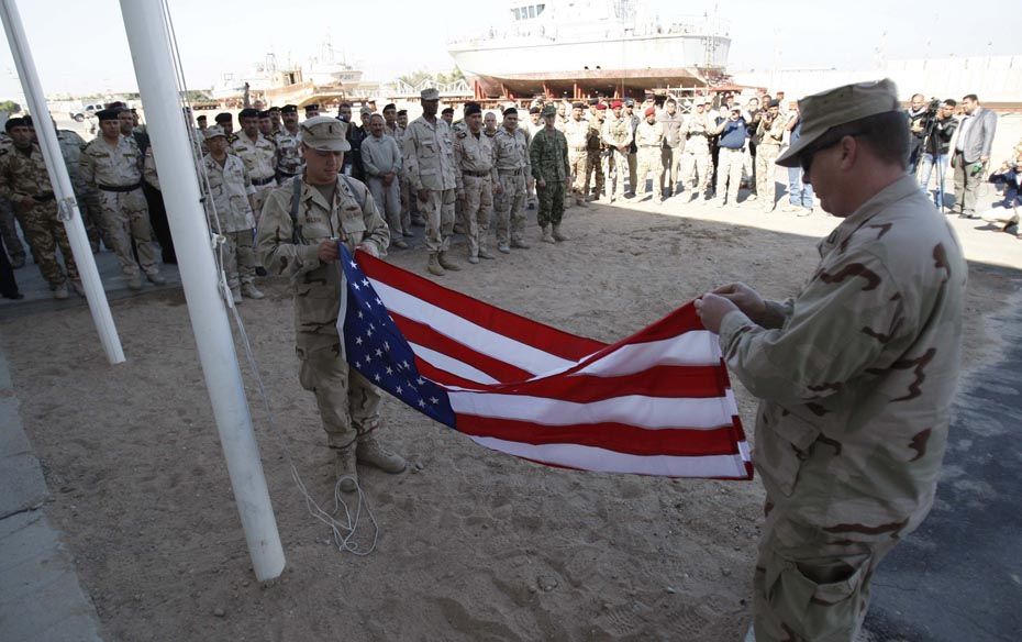 U.S. navy crew fold their national flag as they prepare to hand over their base to Iraqi forces in B