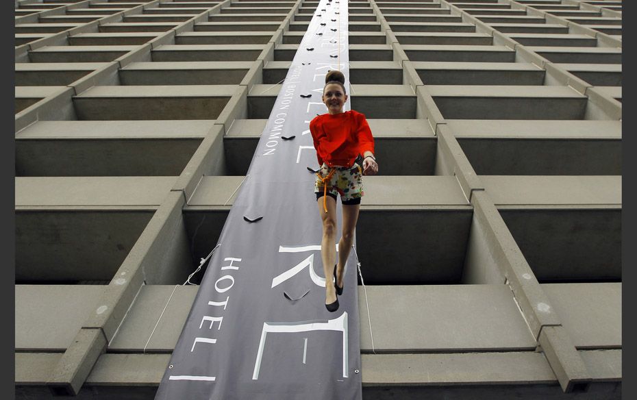 A model from the Boston Rock Gym "walks" face first down the face of the  newly opened Rev