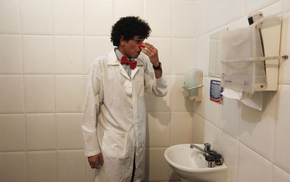 A member of the group Traffic Psychologists fixes his clown nose in a toilet of a petrol station in 