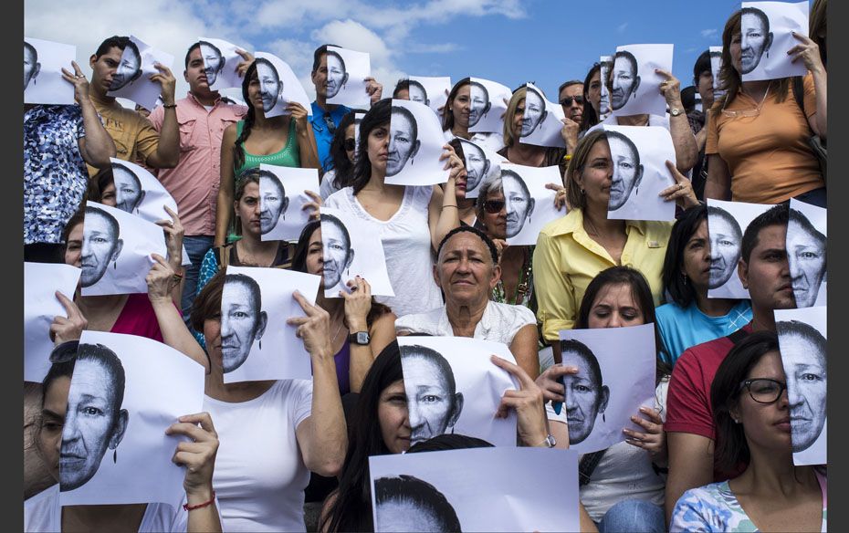 Maria Delgado (C), who lost three children, all victims of violence, poses next to volunteers holdin