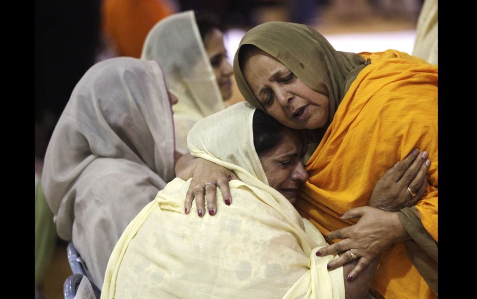 Two woman hug as community members pay respect to six victims of a mass shooting at the Sikh Temple 