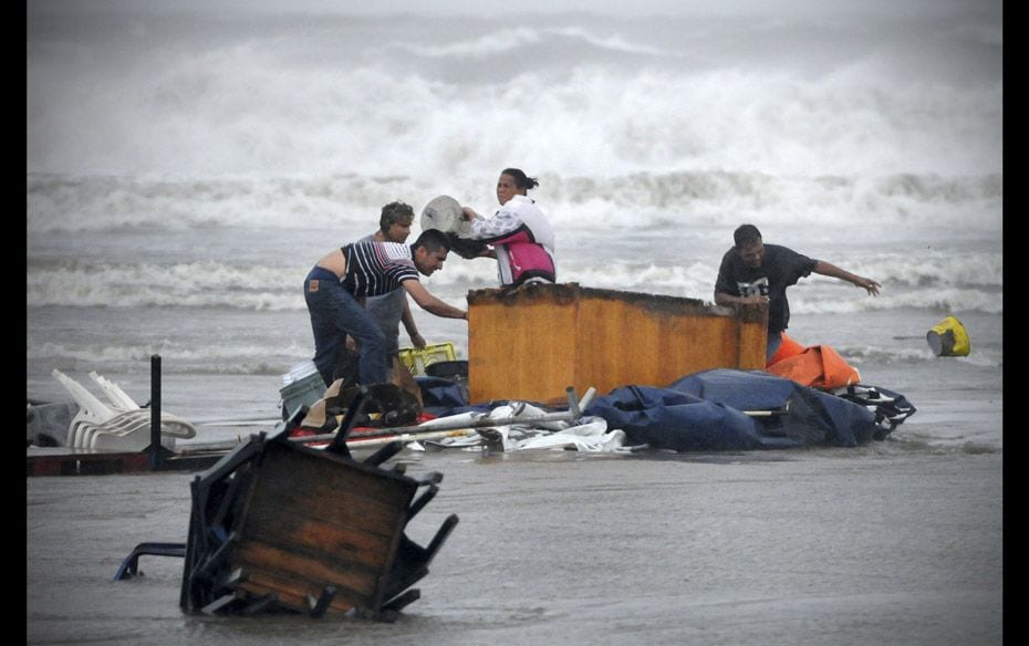 People try to recover things that are being washed away by the flood in Boca Del Rio on the outskirt