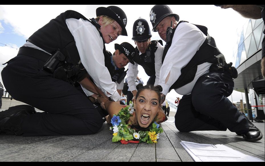 A Femen movement protester is detained by police officers during a naked protest in London on August