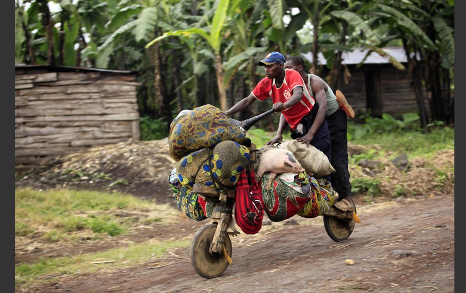 People ride with their belongings on a wooden bicycle as they flee from  renewed fighting between Co