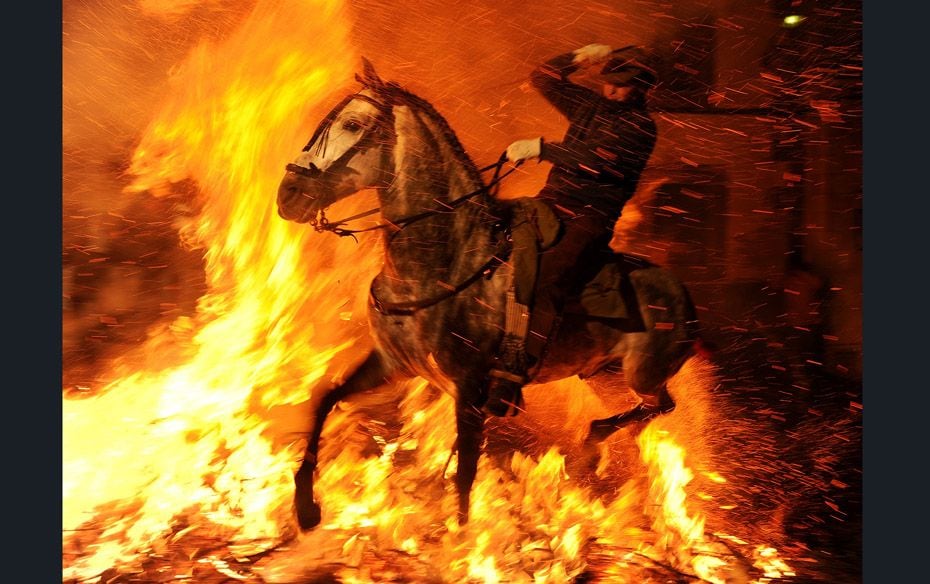 A man rides a horse through a bonfire in the small Spanish village of San Bartolome. In honour of Sa