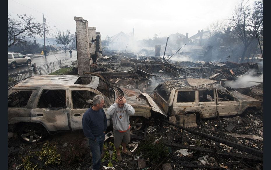 Residents look over the remains of burnt homes in the Rockaways section of New York after Hurricane 