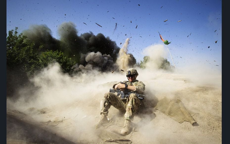 A US army soldier takes cover during a controlled detonation to clear an area for setting up a check