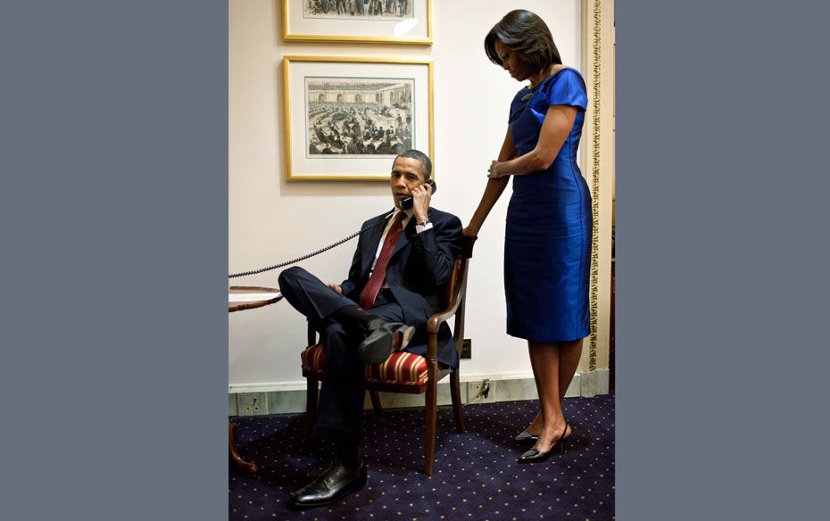 US President Barack Obama with First Lady Michelle Obama while making a phone call to inform John Bu