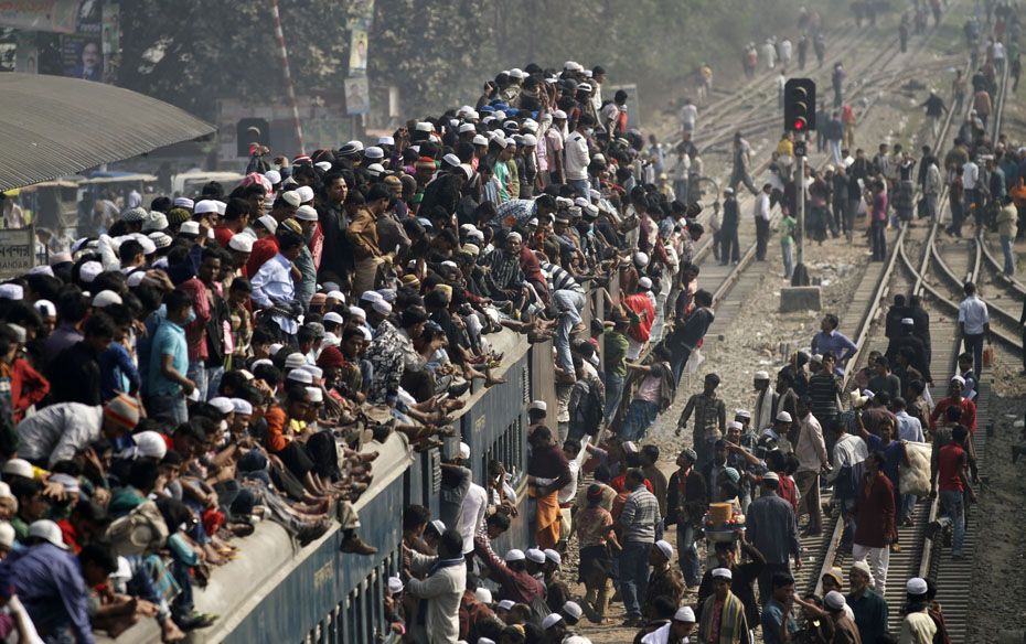 Commuters ride on the roof of a train as they come back to the city after attending the final prayer