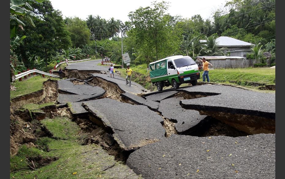 A vehicle transporting a body of an earthquake victim tries to pass through a destroyed road in La L