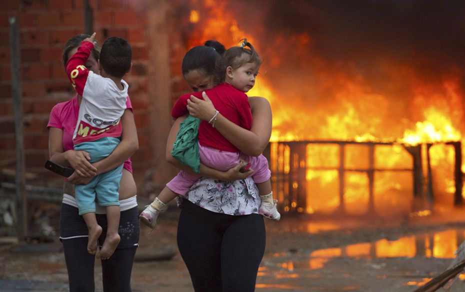 Residents of the Pinheirinho slum walk away from a fire set by other residents, who are resisting ev