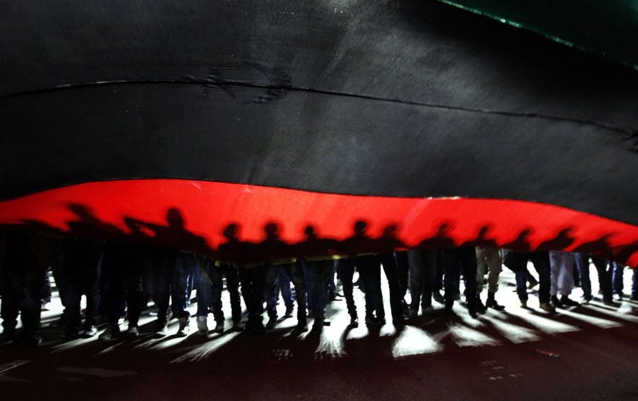 People hold a giant Libyan flag during a march to Martyrs Square in Tripoli                        