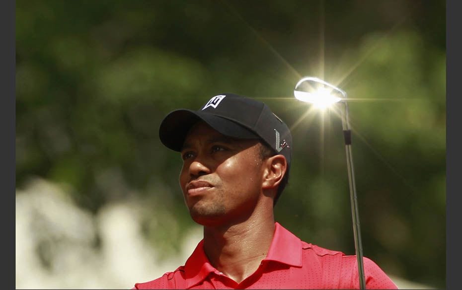 The sun reflects off the club as Tiger Woods hits off on the seventh tee during the final round of t