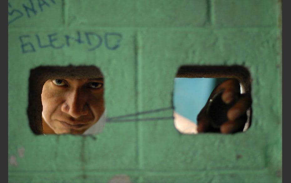 A gang member and inmate looks through a hole on a prison wall in Quetzaltepeque, on the outskirts o