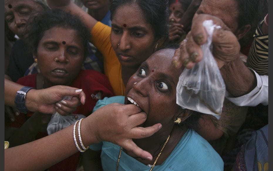 A woman prepares to swallow a live fish that has been dipped in homemade medicine during a camp in t