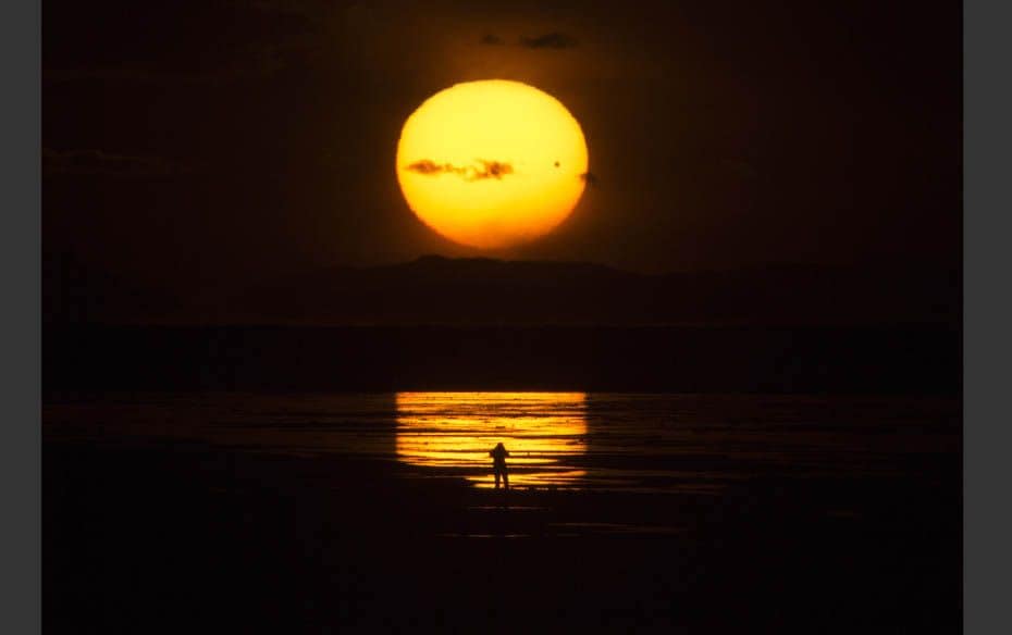 The planet Venus makes a transit as a person watches the sun set over the Great Salt Lake outside Sa