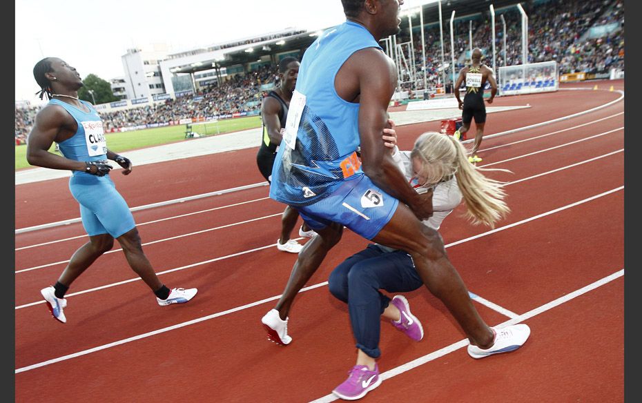  Usain Bolt of Jamaica collides with a flower girl after crossing the finish line to win the me