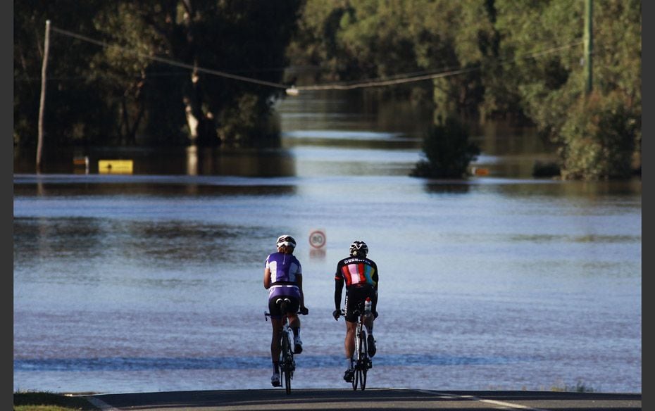 A couple rides near a road submerged in flood waters in Wagga Wagga, Australia                      