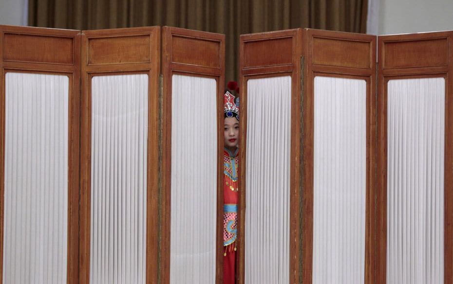 A girl looks out from behind a screen as she waits to perform during celebrations for the upcoming I