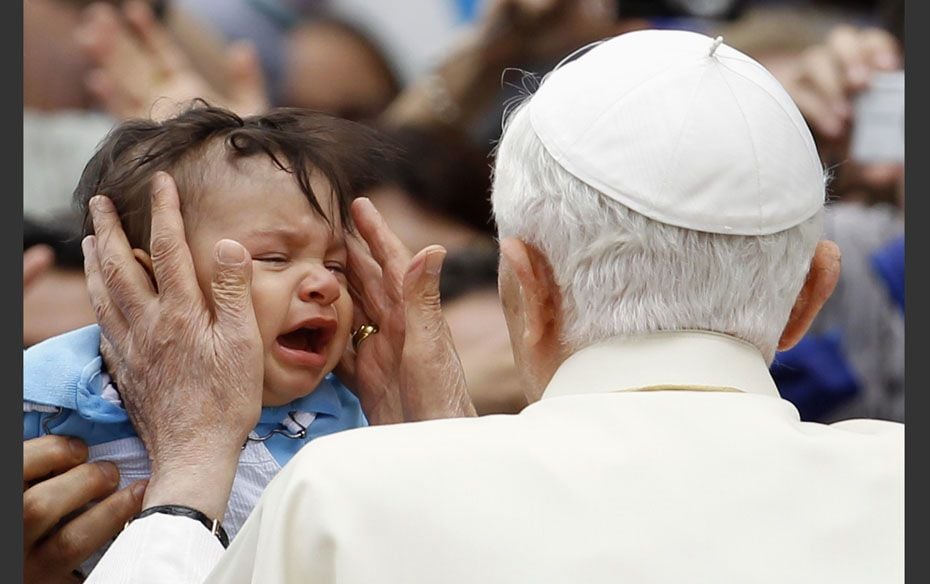 A baby cries as Pope Benedict XVI strokes his cheeks after the weekly audience in St. Peter's Sq