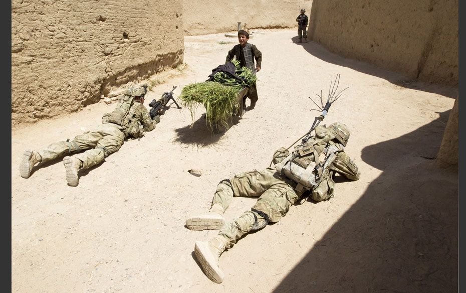 An Afghan boy pushes a wheelbarrow next to U.S. Army soldiers of the Battle company, 1-508 Parachute