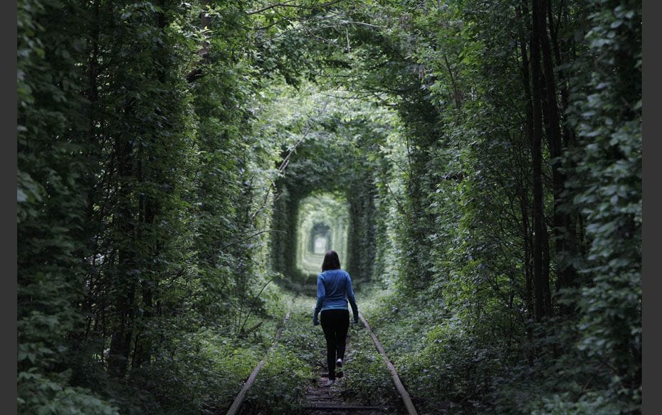 A girl walks on a disused railway track through what is known locally as the "Tunnel of Love&qu