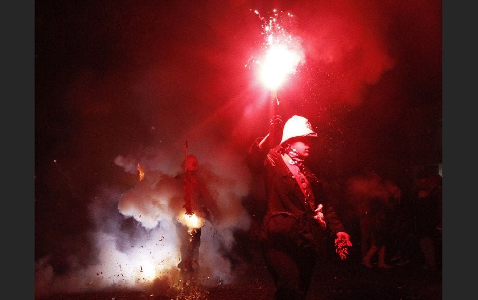 Participants hold burning torches in one of the series of processions during Bonfire night celebrati