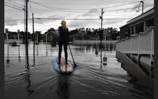 Zoe Jurusik, 20, paddle-boards down a flooded city street in the aftermath of Hurricane Sandy in Bet