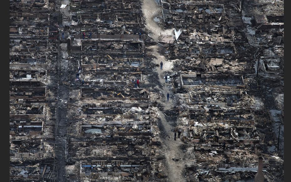 Residents walk past burnt houses in Breezy Point, a neighbourhood located in the New York City borou