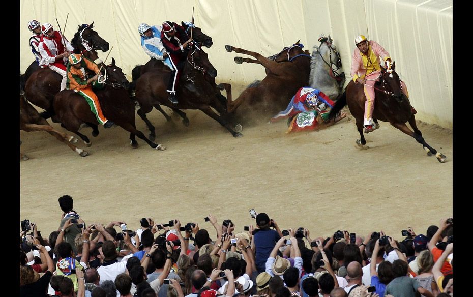 An Italian Carabinieri policeman falls down during the Palio race in Siena’s main square on Au