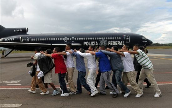 Federal policemen escort a group of prisoners towards a plane bound for an undisclosed location at t