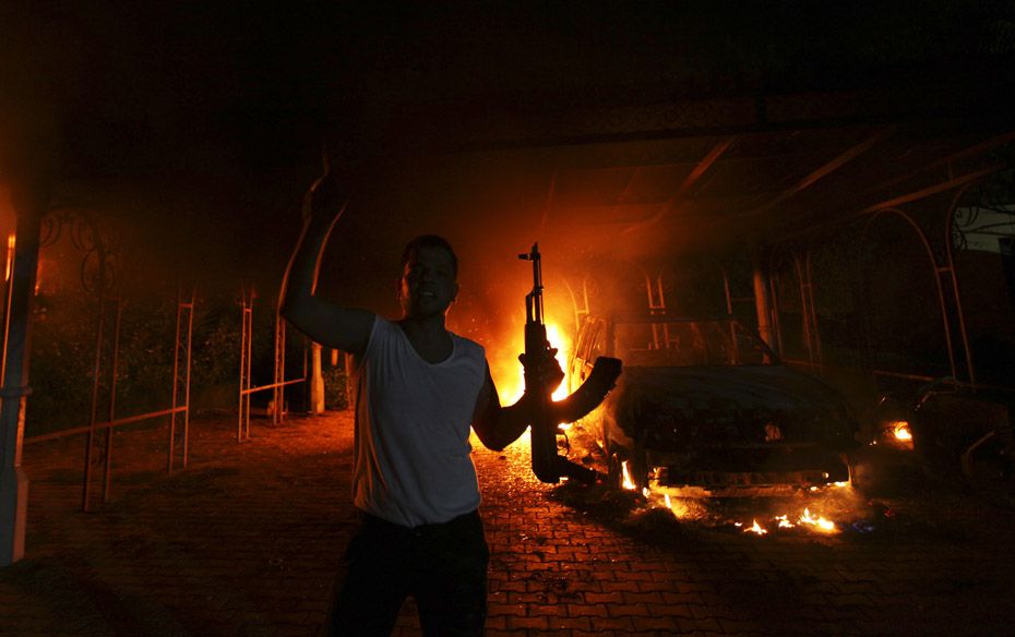 A protester reacts as the US Consulate in Benghazi is seen in flames during a protest by an armed gr