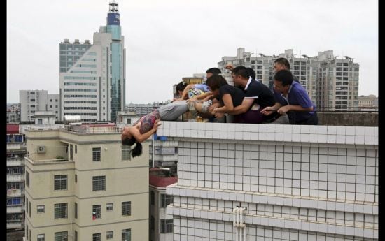 Rescuers and relatives stop a woman from committing suicide by jumping off a building in Zhanjiang, 