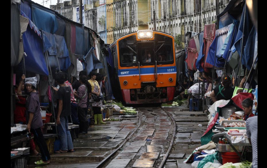 Thai vegetable vendors pull back awnings and their produce off a railway track to allow a cross-coun