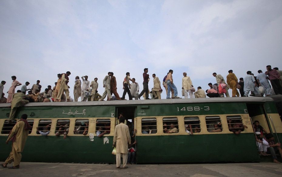 Passengers climb aboard the carriage of a train at a railway station in Lahore on August 18, 2012. T