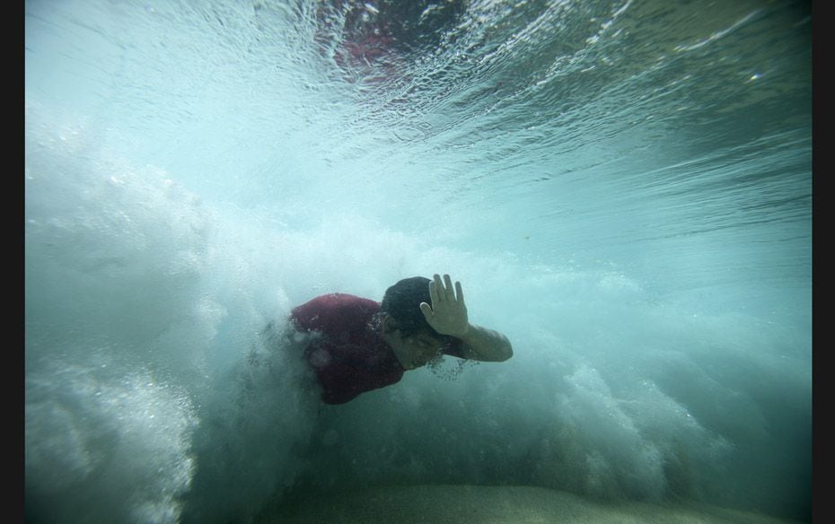 A bodysurfer punches through a wave at the Ehukai sandbar near the surf break (known as 'Pipelin