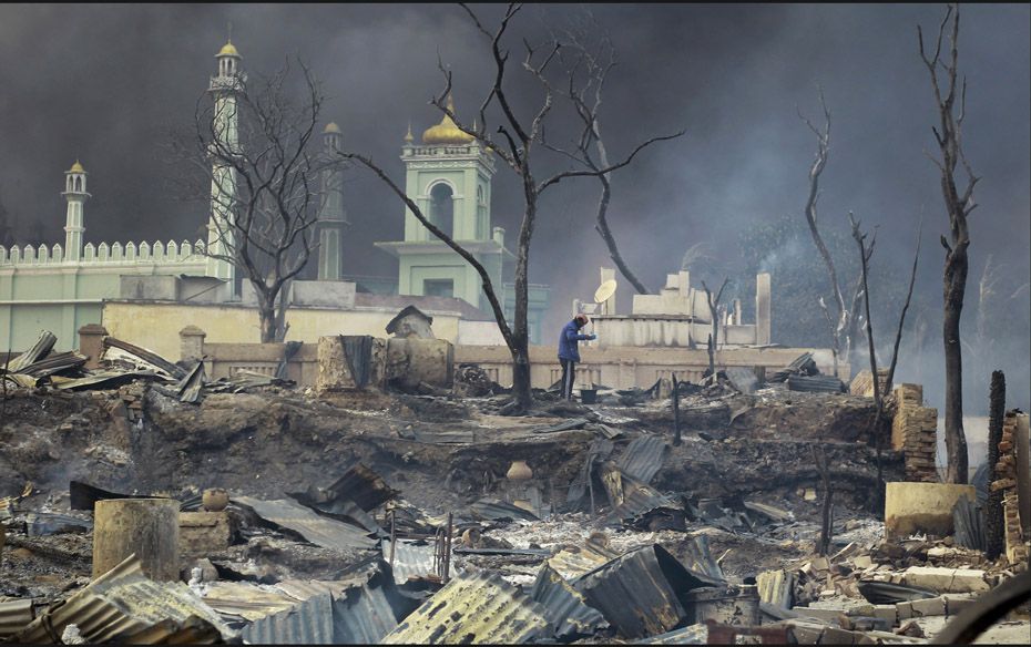 A man stands in front of a mosque as it burns in Meikhtila on March 21. The central Myanmar town dec