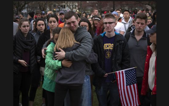 Scott Turner (C) is hugged by friends as he weeps at a vigil for bomb victims, a day after two explo