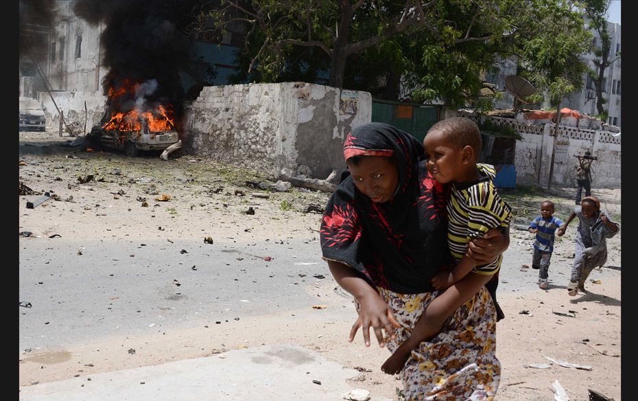 A mother runs with her child in Mogadishu, after a suicide bomber attack in the regional court premi