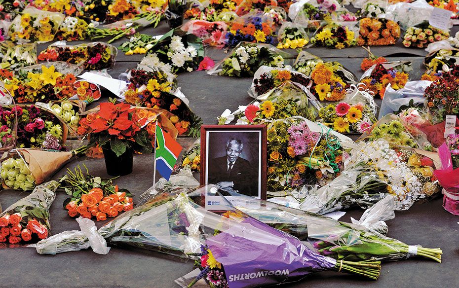 Flowers left by mourners surround a portrait of Nelson Mandela in Sandton district of Johannesburg. 