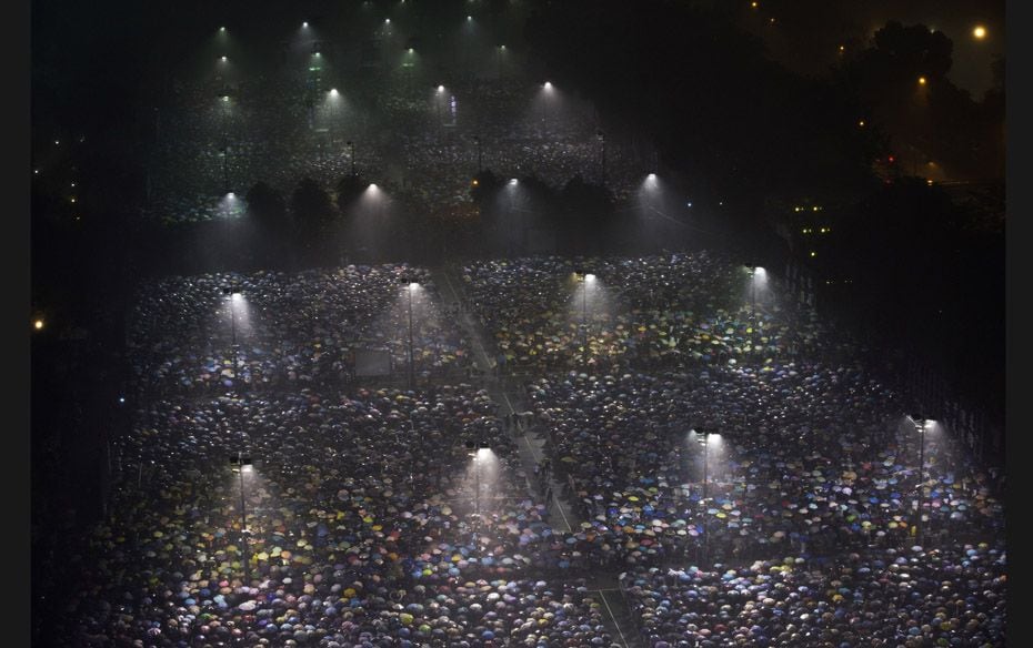 Tens of thousands of people participate in a candlelight vigil under heavy rain at Hong Kong's V